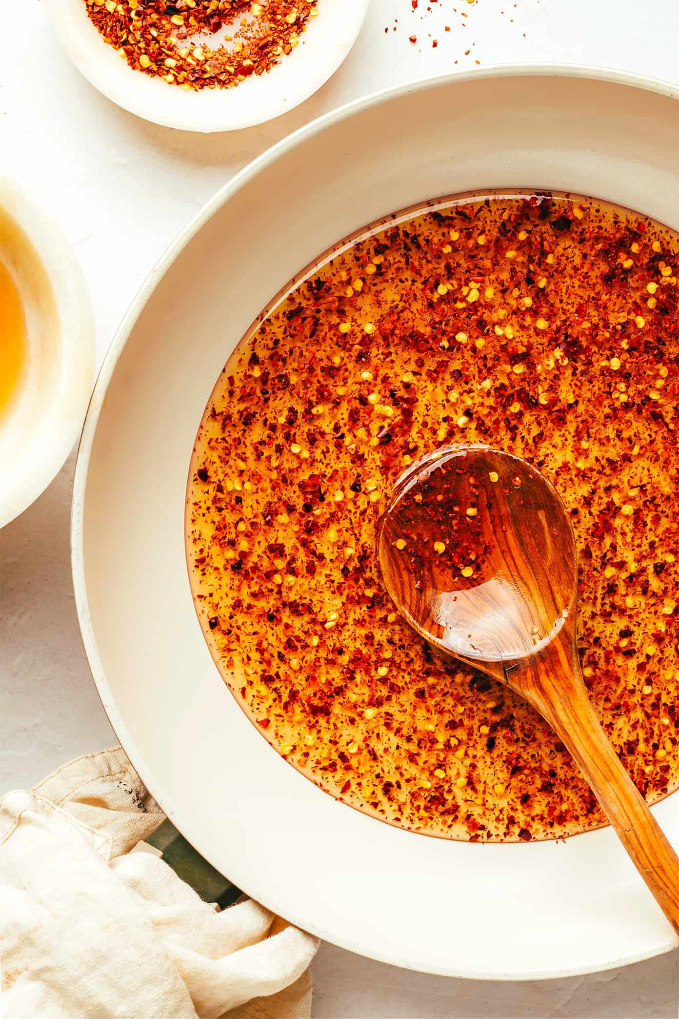 Spicy honey in a bowl with a wooden spoon on a light background